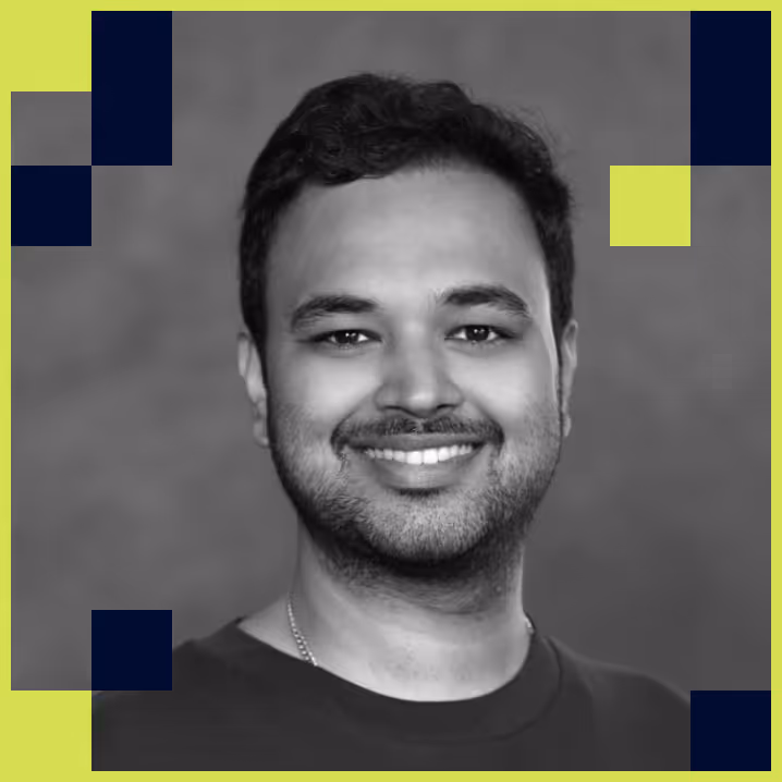 Smiling man with short dark hair and beard, wearing a dark shirt, against a gray background with a bright lime and navy geometric border.