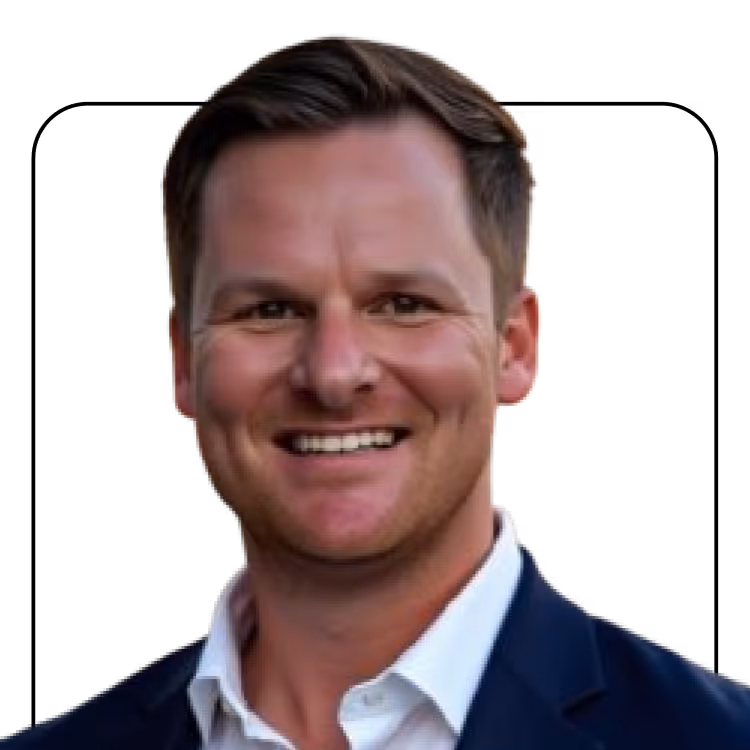 Smiling man with short brown hair wearing a white shirt and dark blazer against a black background.