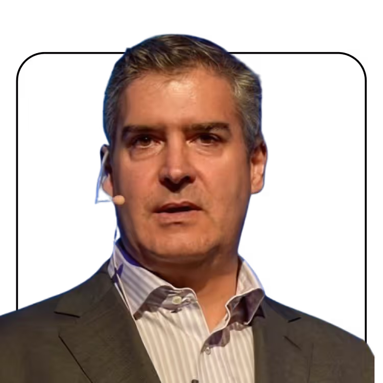 Man with gray hair wearing a striped shirt and dark suit jacket speaking with a headset microphone.