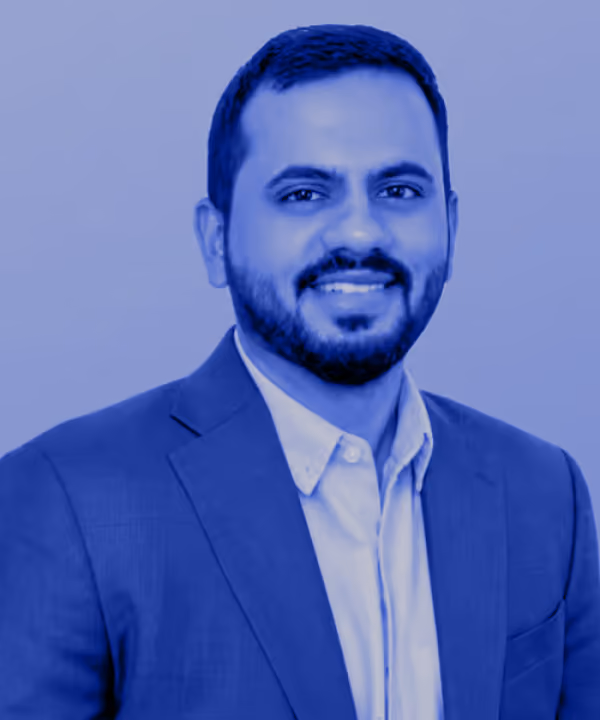 Portrait of a smiling man with short hair and beard wearing a suit jacket over a collared shirt.