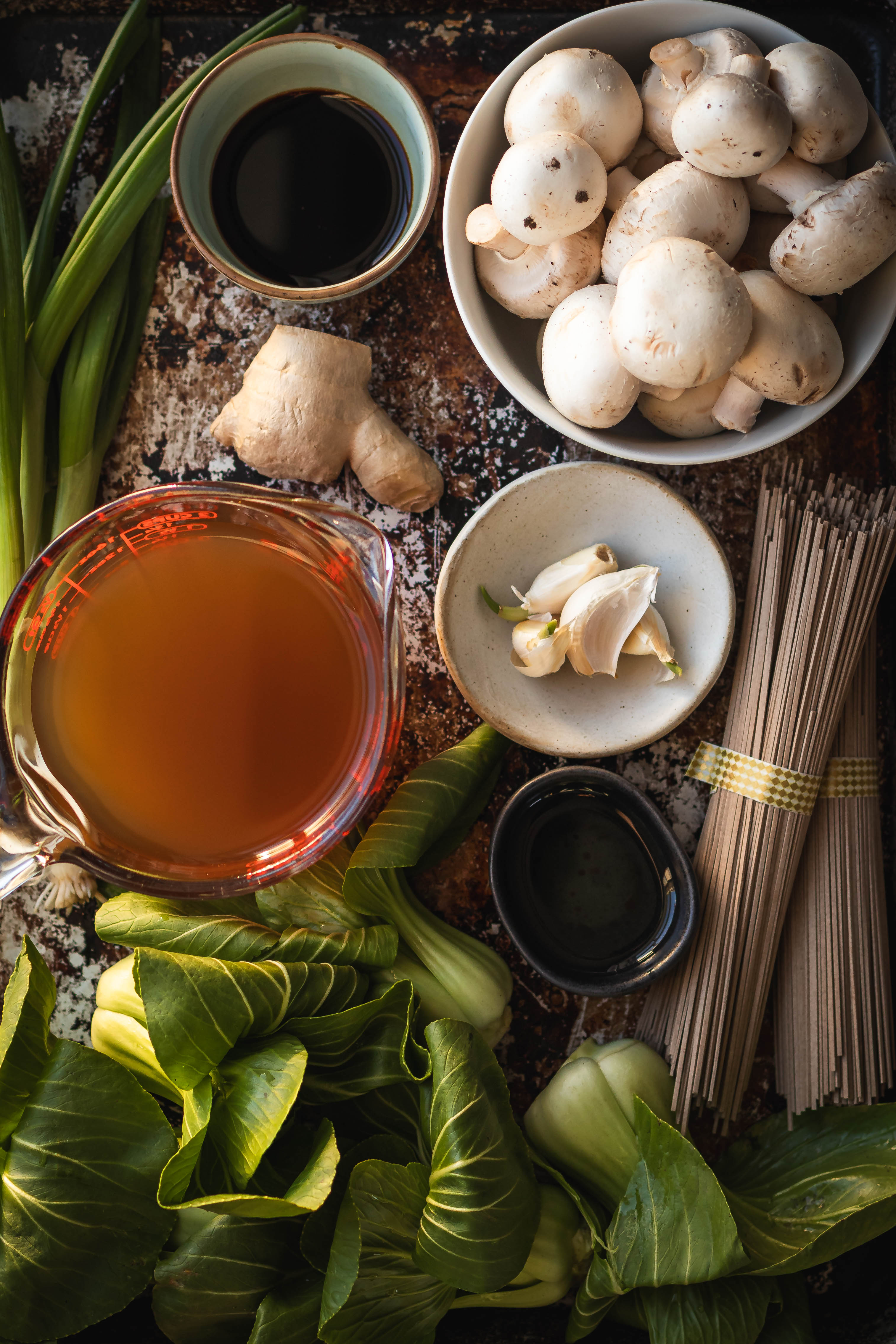 Ingredients for bok choy soup including mushrooms, scallions, ginger, garlic, vegetable stock and bok choy on a tray
