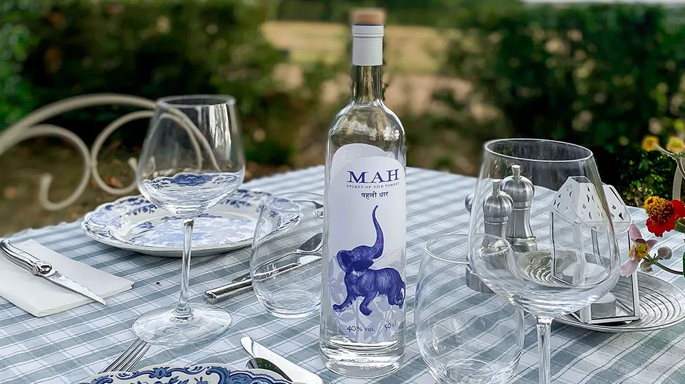 MAH Spirit bottle and glasses set on an outdoor table
