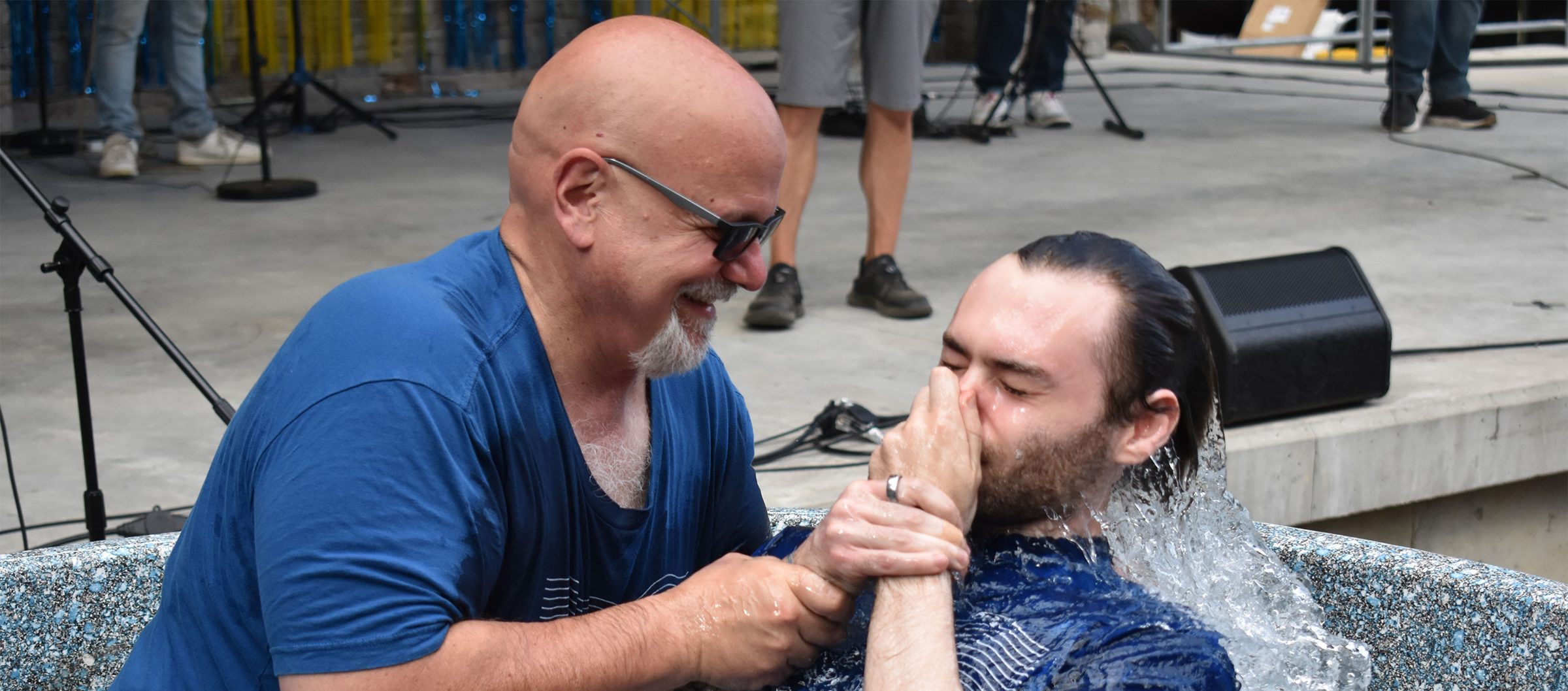 Smiling man baptizing a young man in the water at an outdoor Granite United baptism