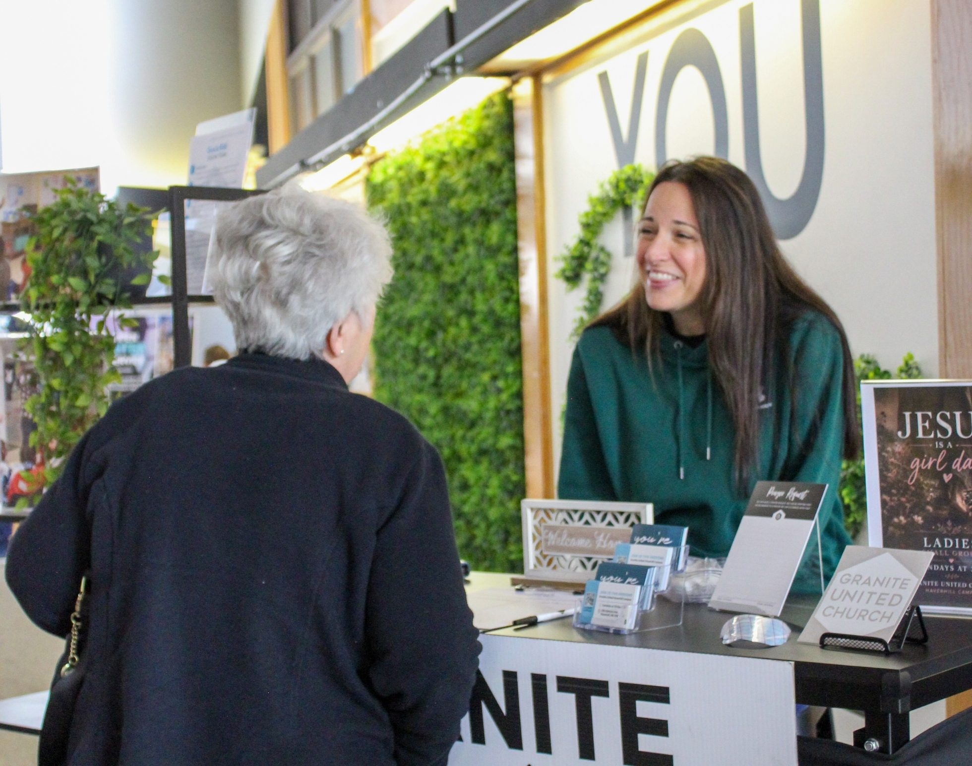 Smiling volunteer welcoming a guest at the Granite United Church welcome desk