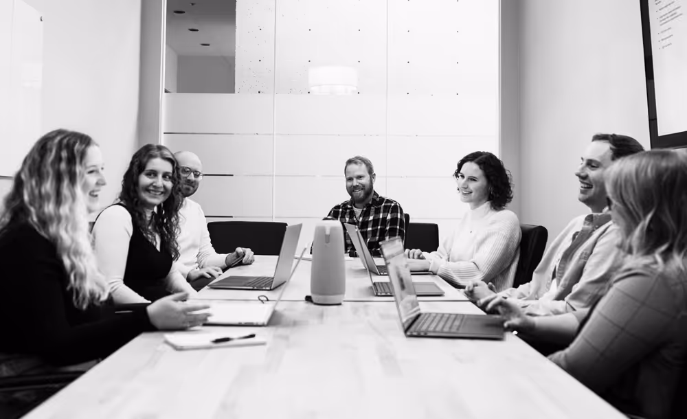 Quill Creative team sitting around a conference table talking and smiling with each other