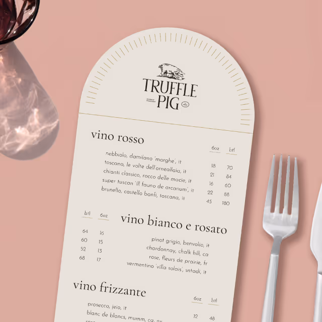 Arch style cream Truffle Pig Oshkosh menu on a pink table cloth with silverware