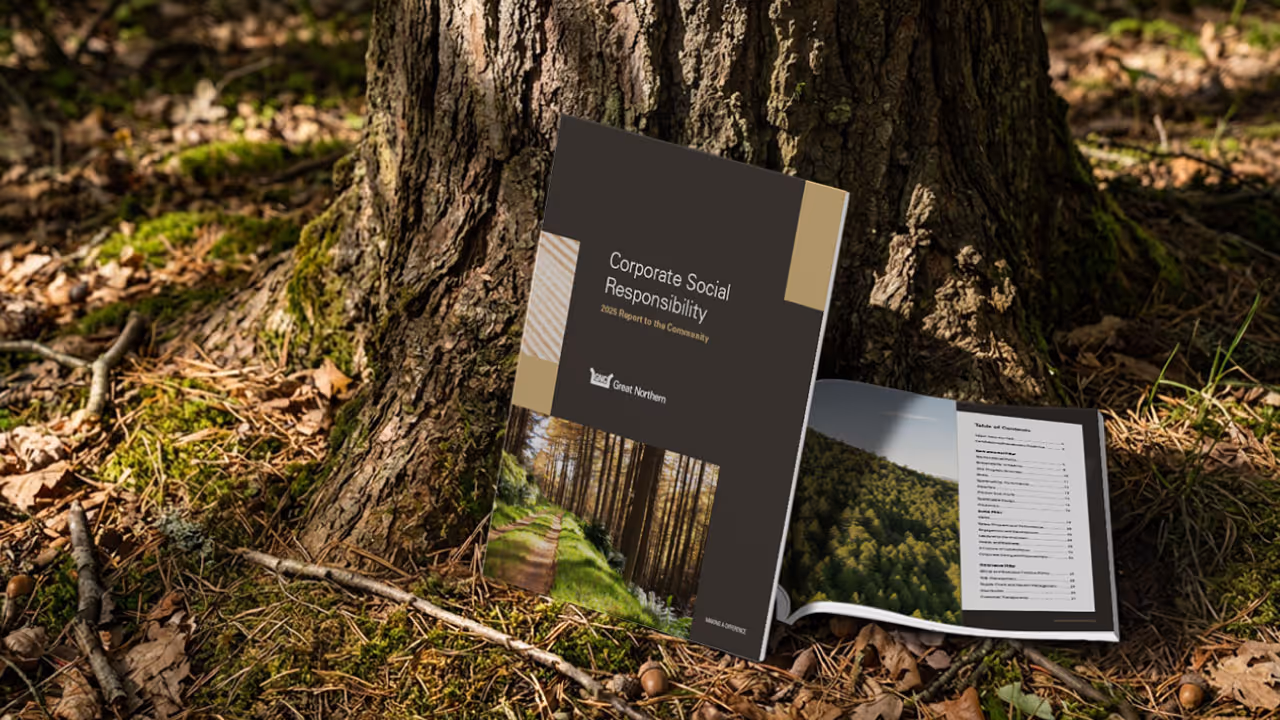 Great Norther Corporation Report to the Community Report and open spread sitting next to a tree outside