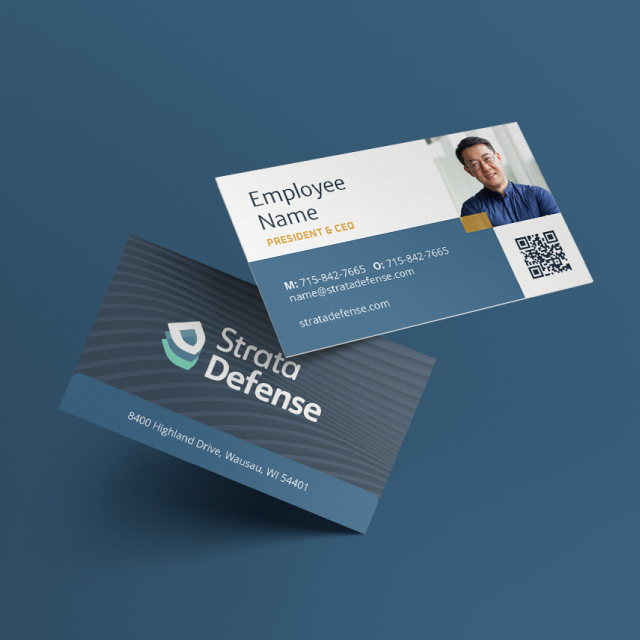 Two Strata Defense business cards on a blue surface; one showing company logo and address, the other showing employee photo, name, title, contact details, and QR code.