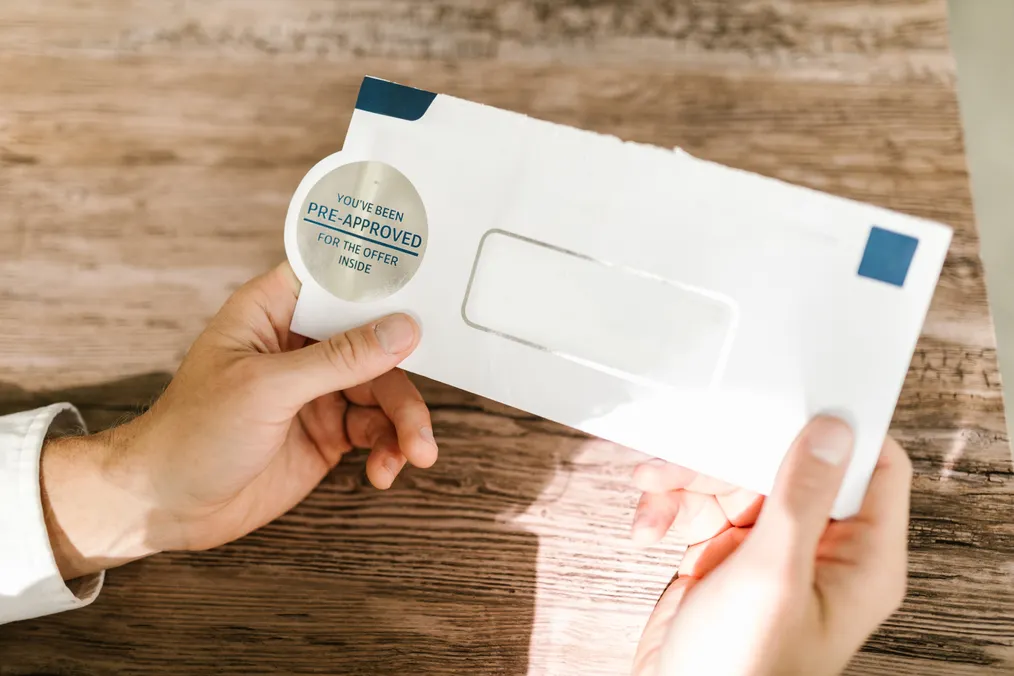 Hands open an envelope marked pre-approved