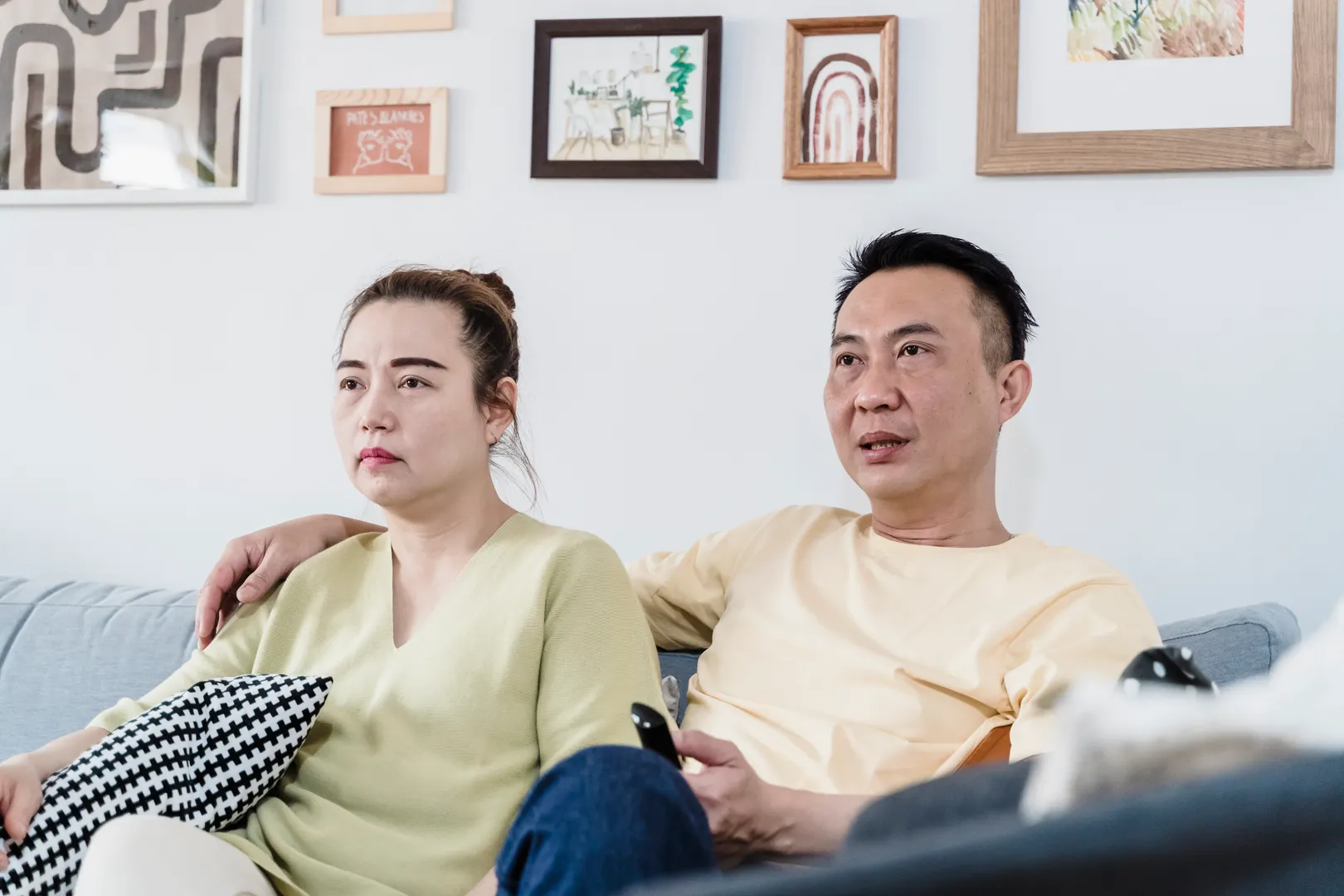 A couple sitting on a comfortable sofa at home in a cozy living room, enjoying a relaxed moment together.
