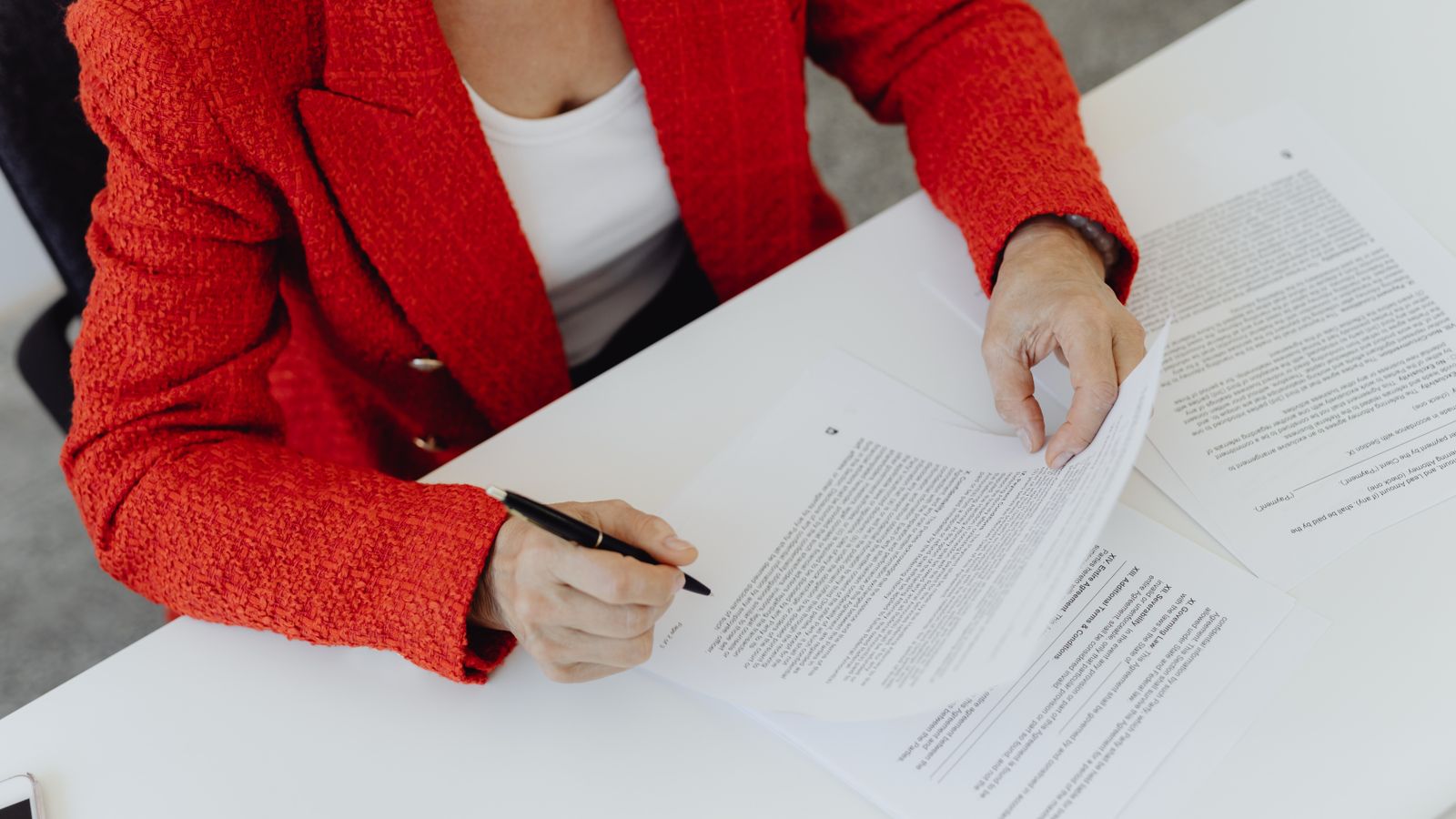 A woman works through the fine print of a loan contract with a pen in hand