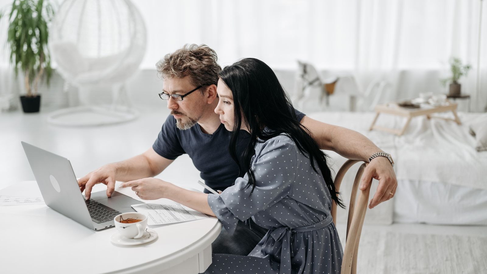 A couple compare loan options together on a laptop at their kitchen table