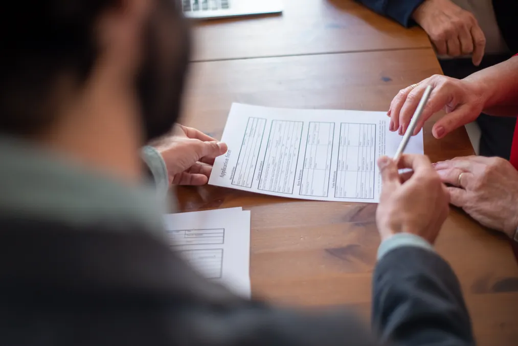 Three people review a form together at a wooden table