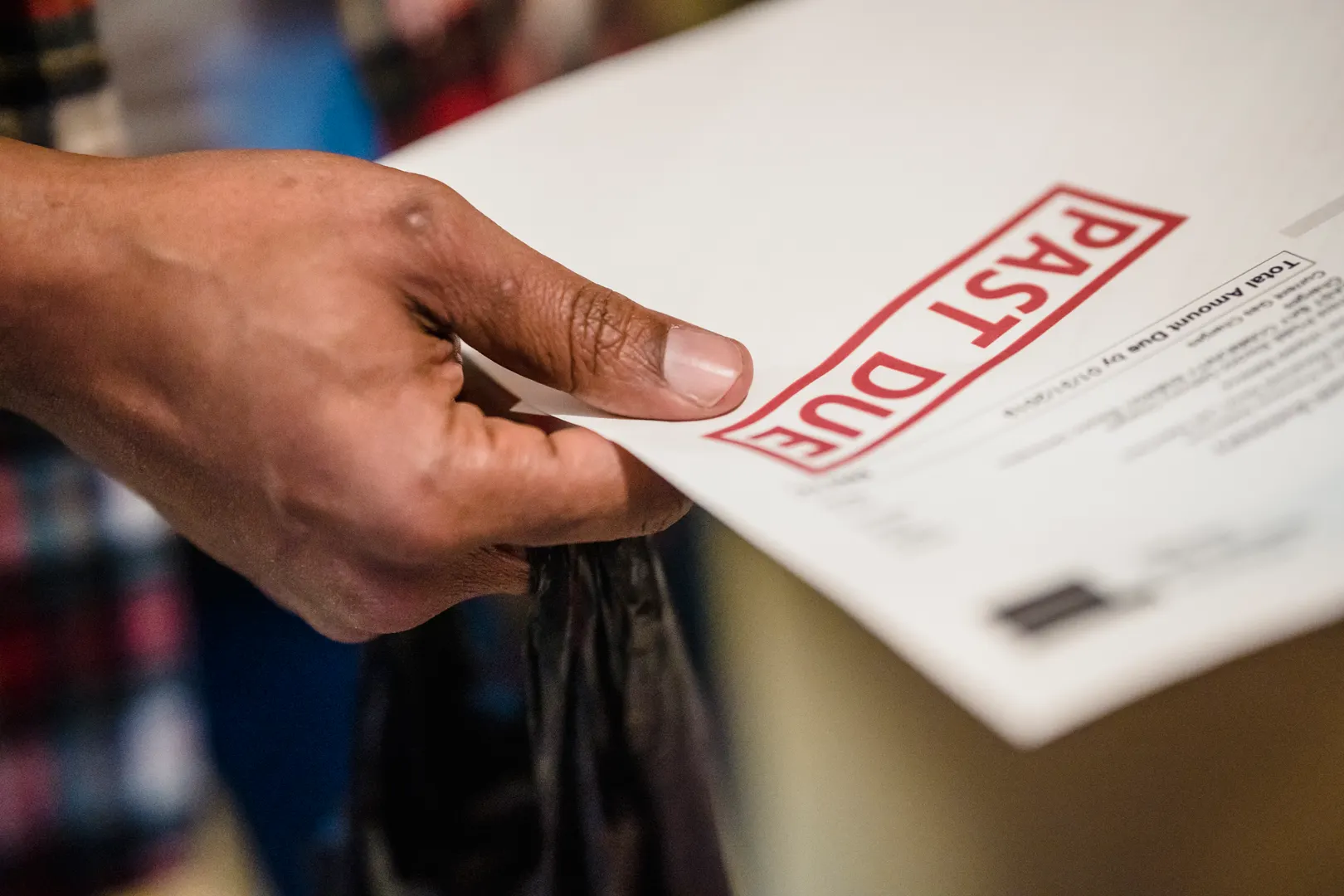 A hand holds a notice stamped past due