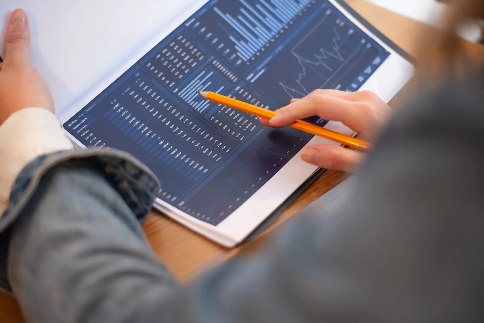 Hands use a tablet to review financial charts