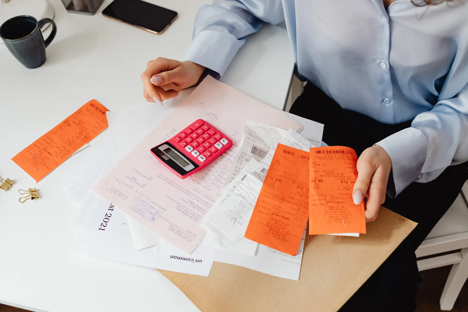 A faceless person reviews receipts with a calculator