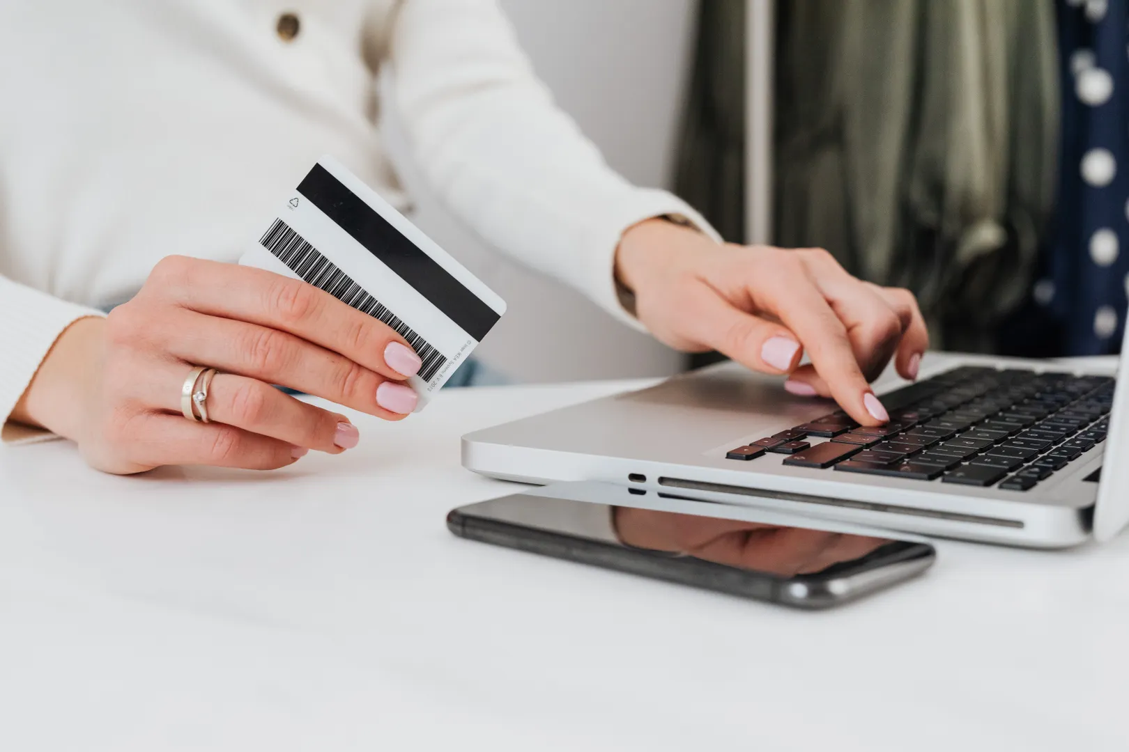 Hands hold an unbranded card beside a laptop