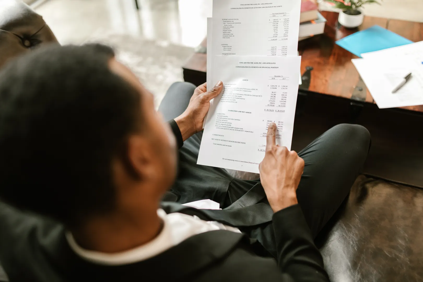 An over-shoulder person reviews a detailed financial statement