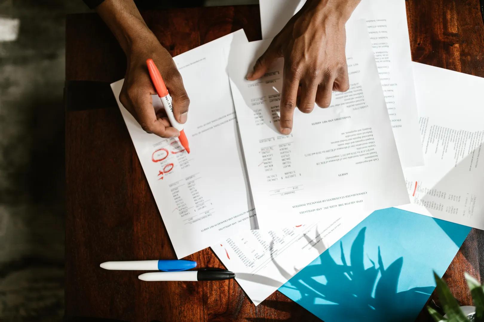 Hands highlighting figures across several financial documents