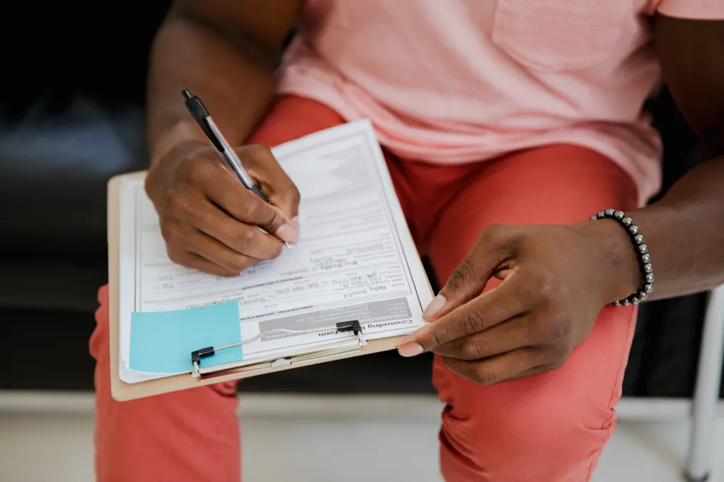 Close-up of a person completing a paper application form
