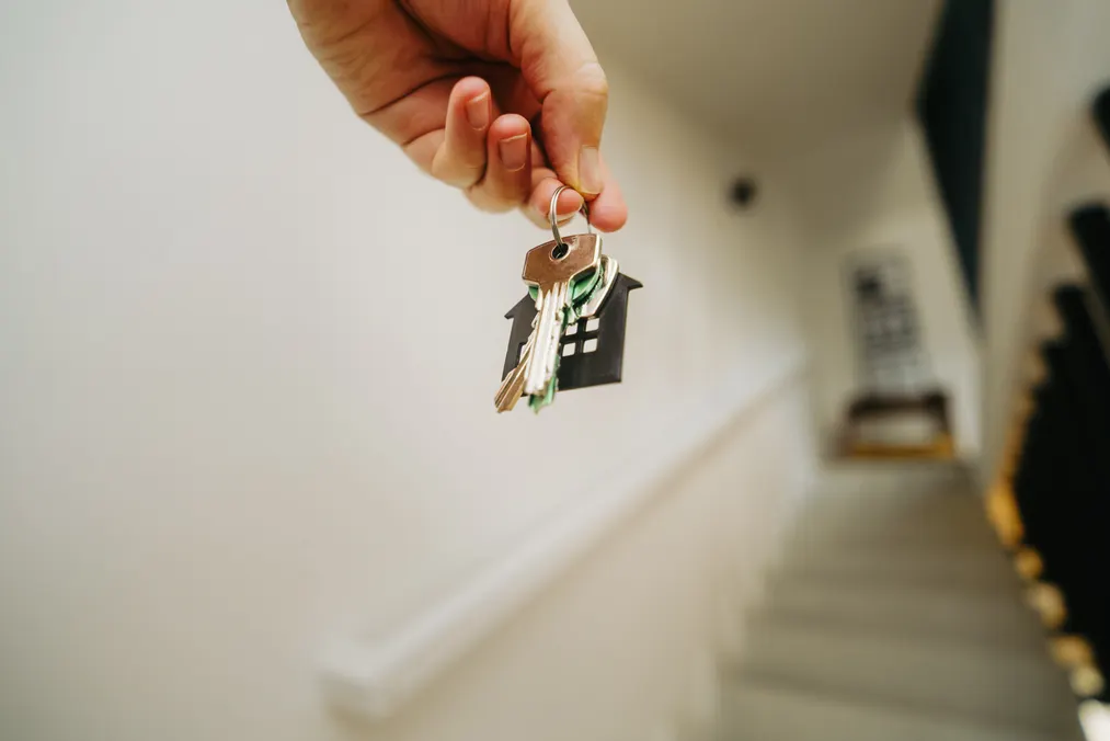 Close-up of a hand holding house keys inside a home