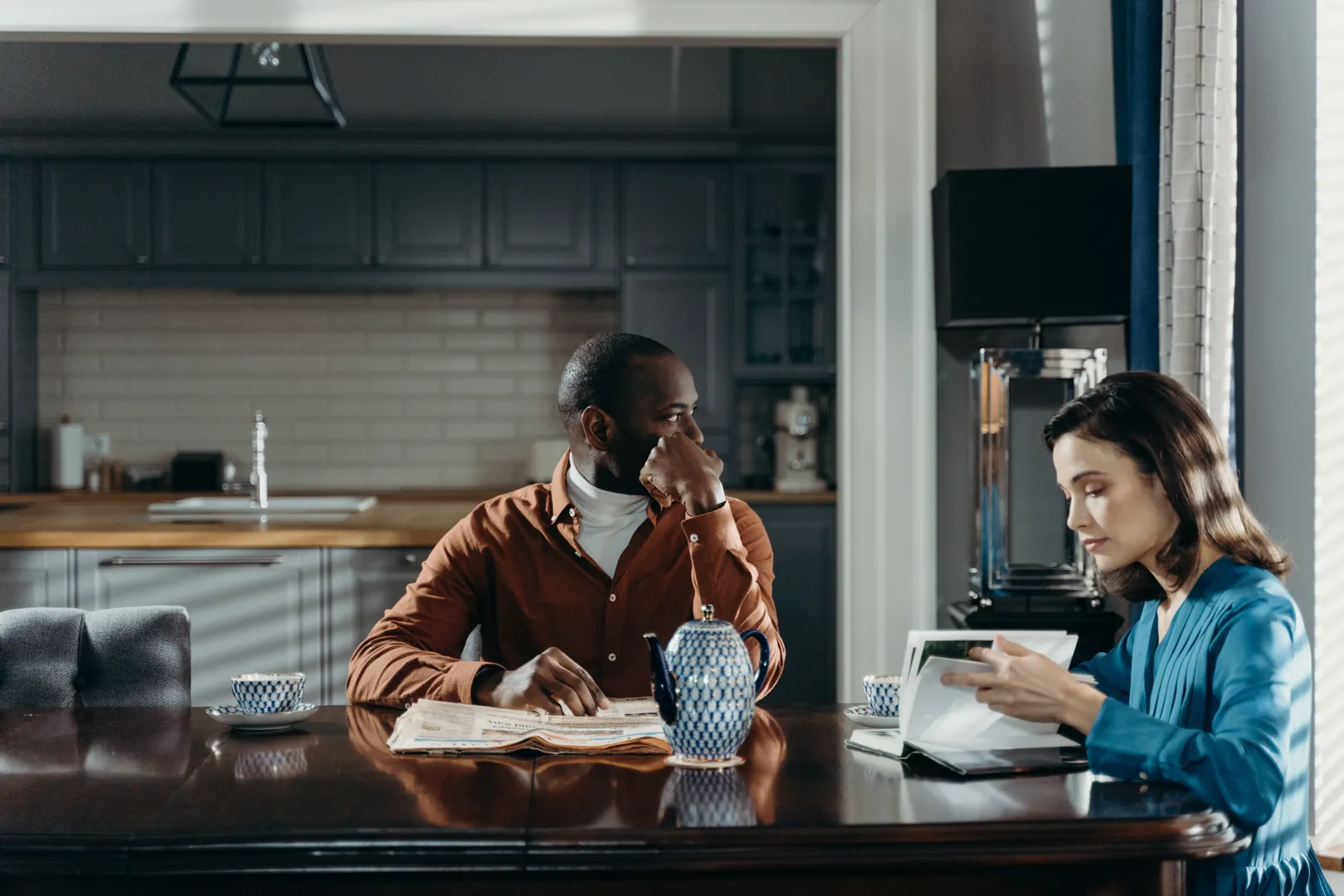 A couple reviewing a notebook and laptop at their kitchen table