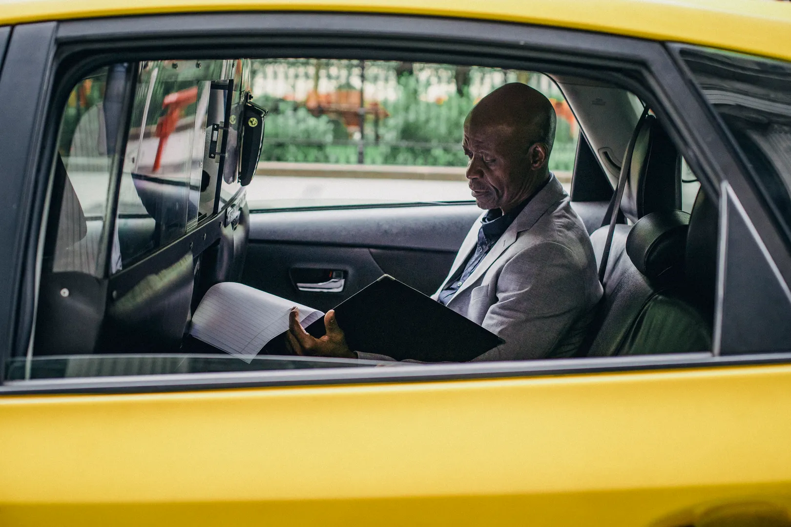 A man reviewing documents while seated inside a car