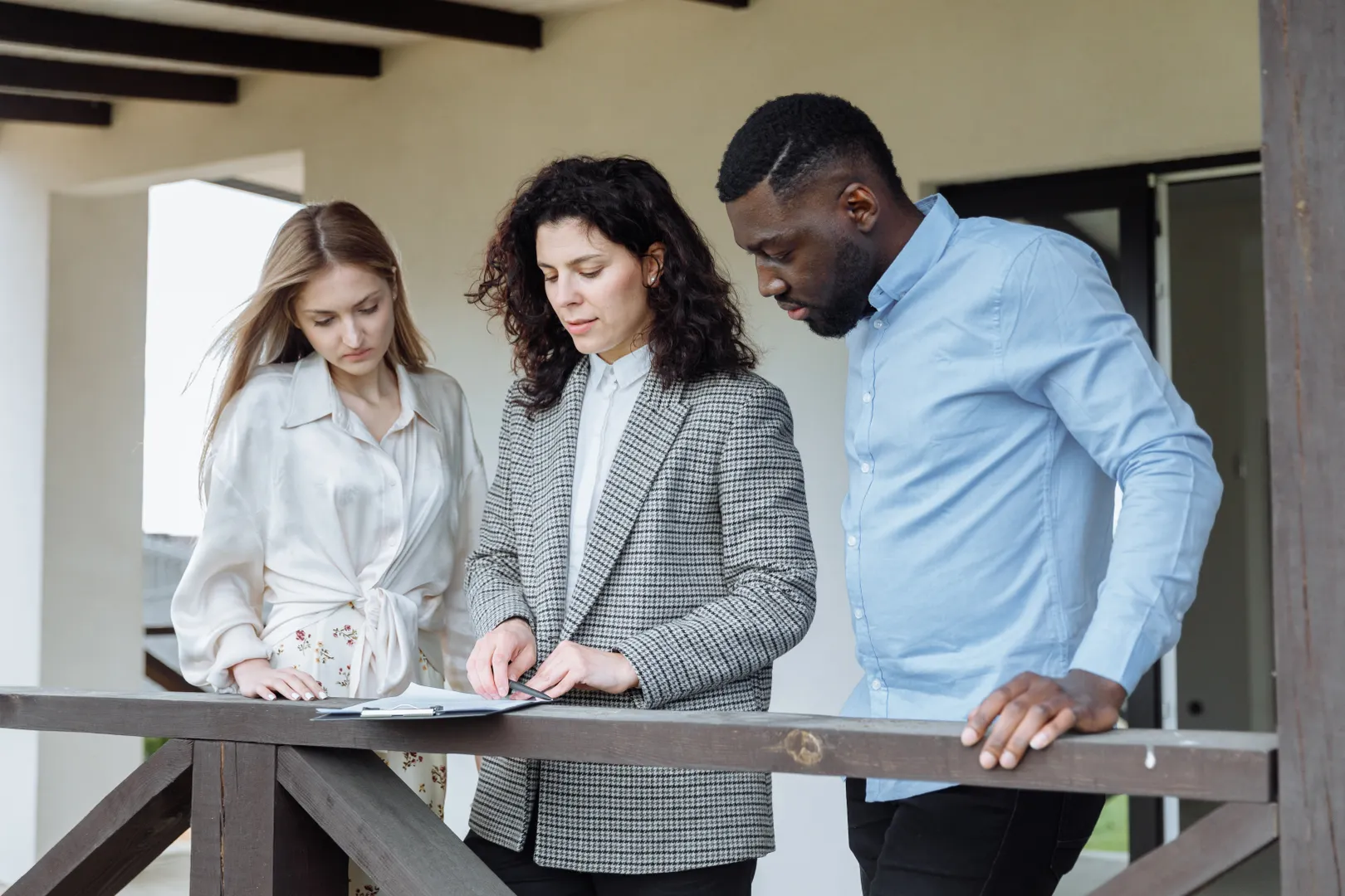 Three adults standing together and reviewing documents