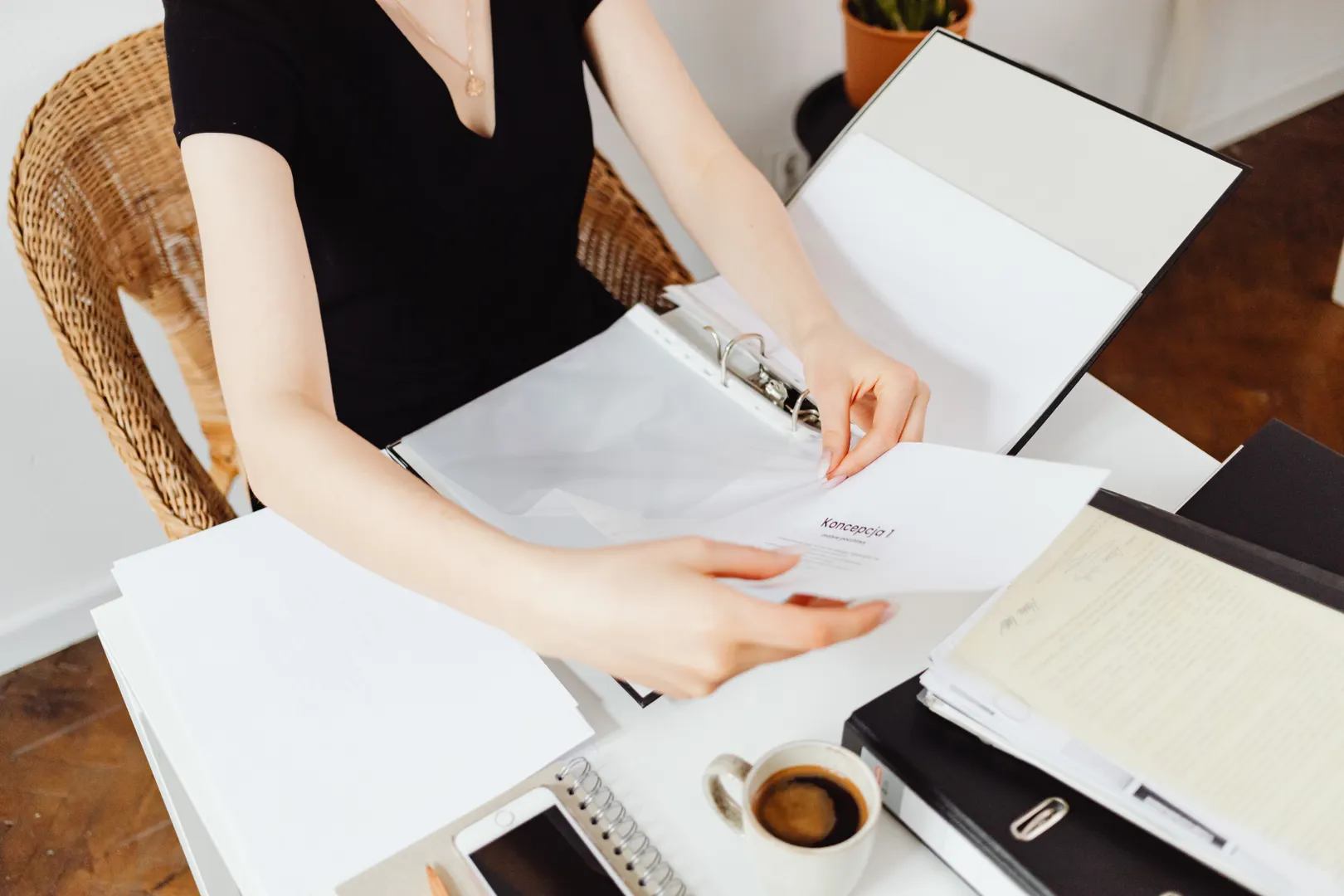 A woman organising paperwork in an open binder at a desk