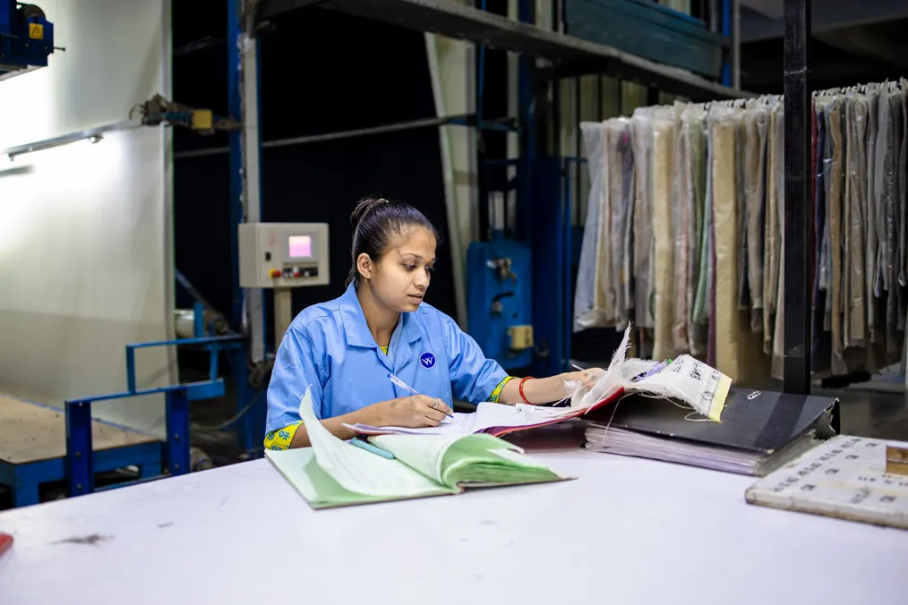 A factory worker reviewing paperwork at her workstation