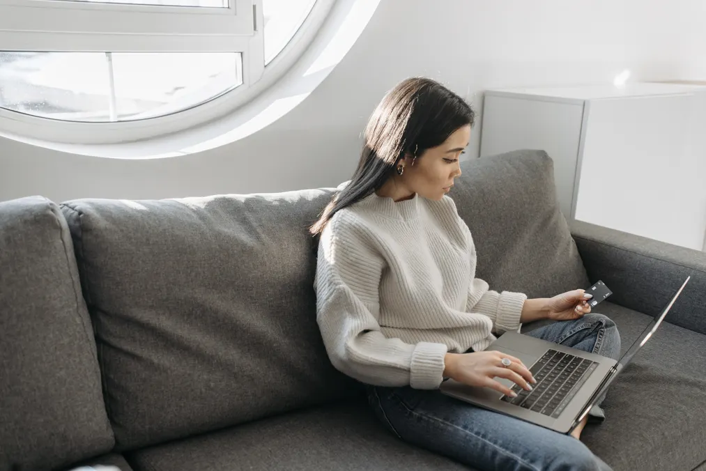Woman checking a plain card while using a laptop at home