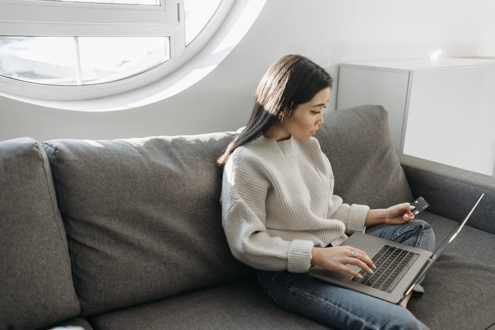 Woman checking a plain card while using a laptop at home