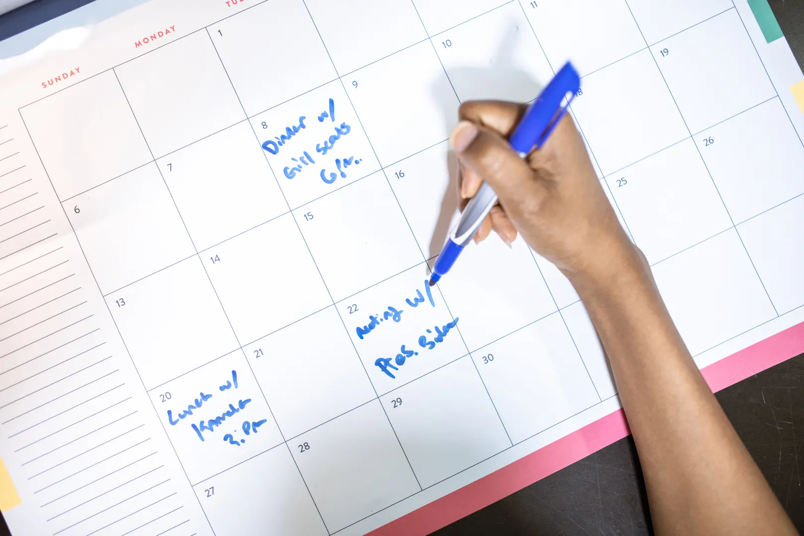 Hand writing appointments on a large paper calendar