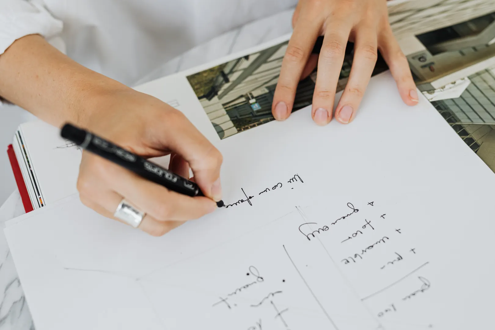 Hands writing calculations on paper at a desk