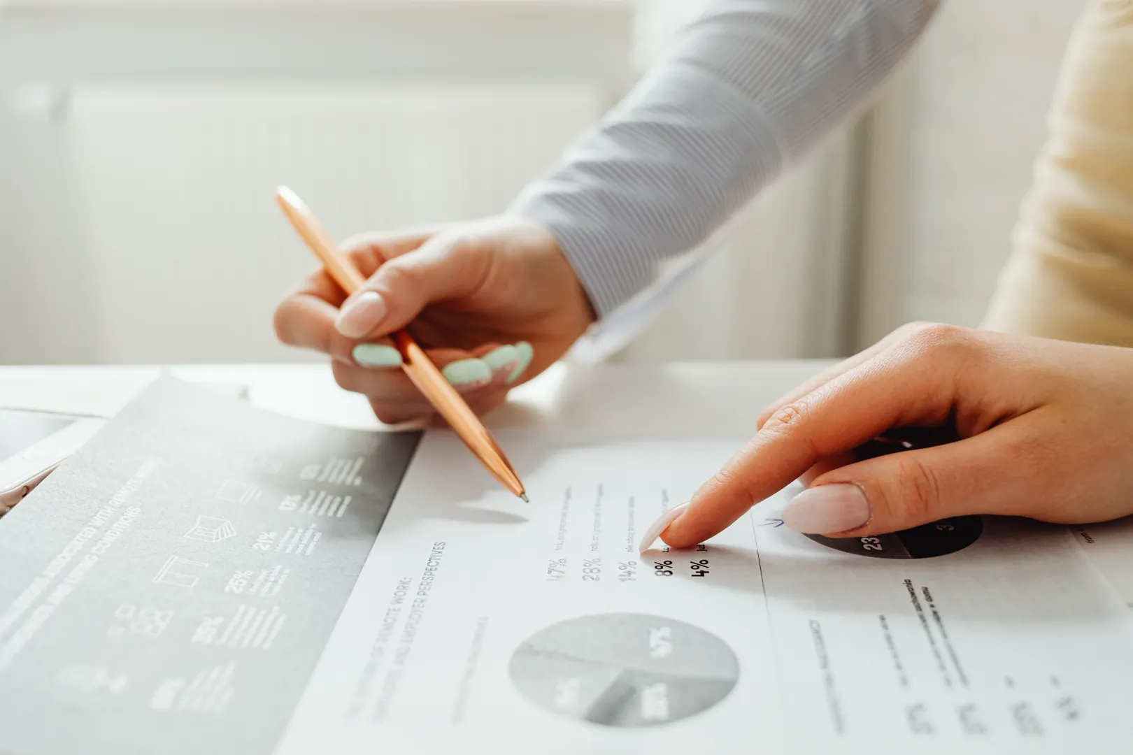 Two hands pointing across a printed financial report