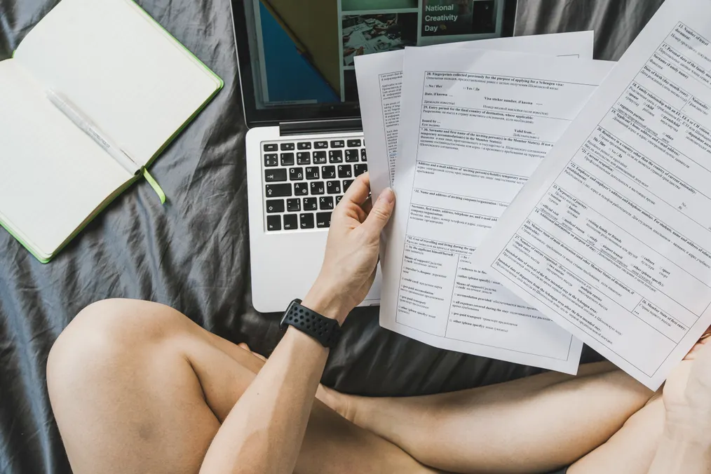 Person reviewing several forms beside a laptop