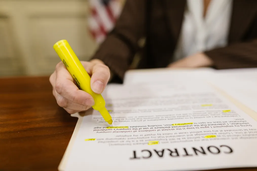 Hand highlighting clauses in a printed contract