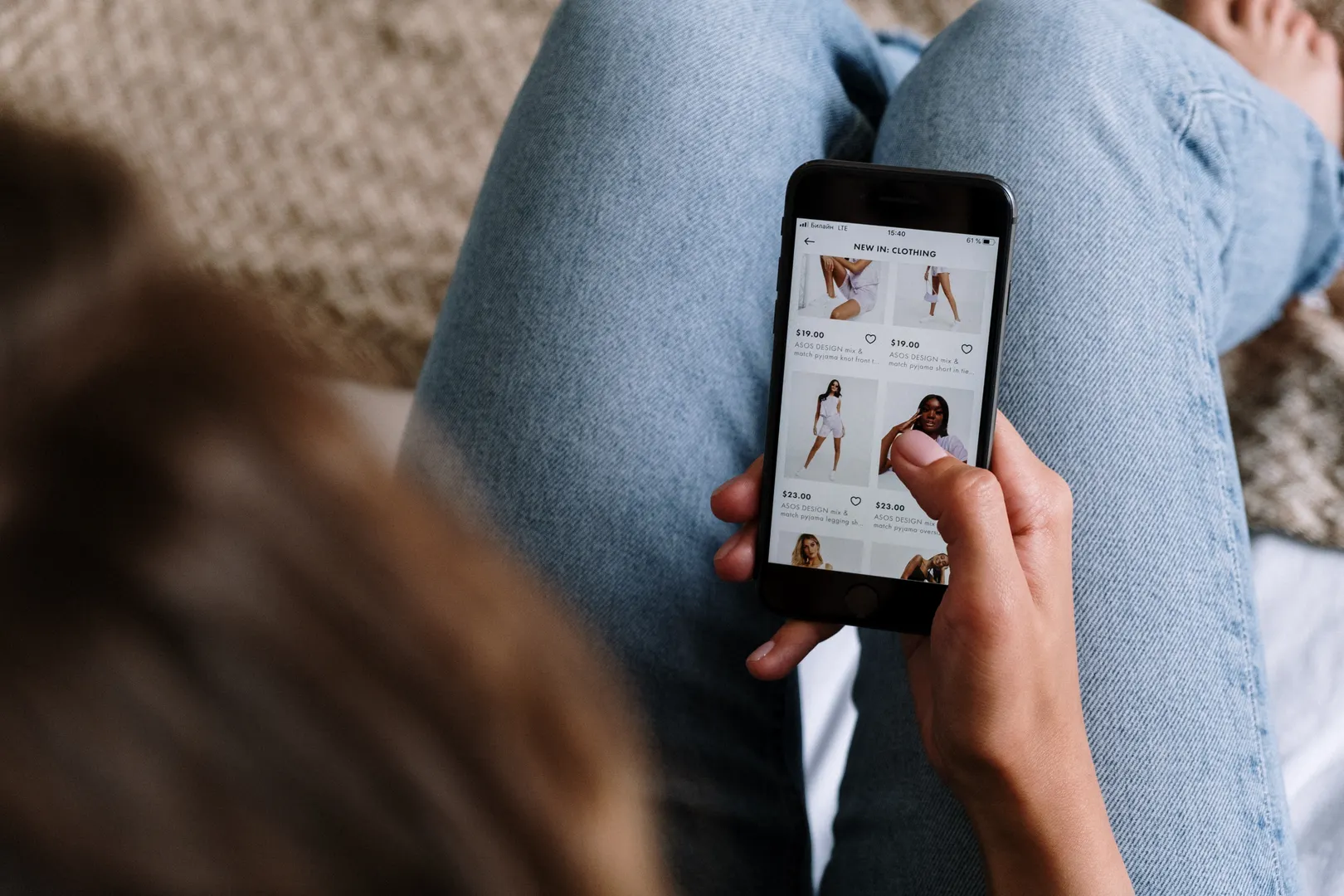 Overhead view of a person browsing a clothing shopping app on their phone at home