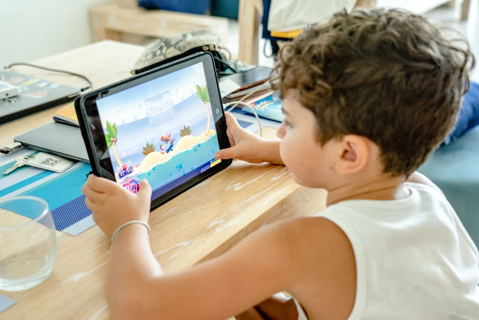 A young boy taps the screen of a tablet while playing a game at home