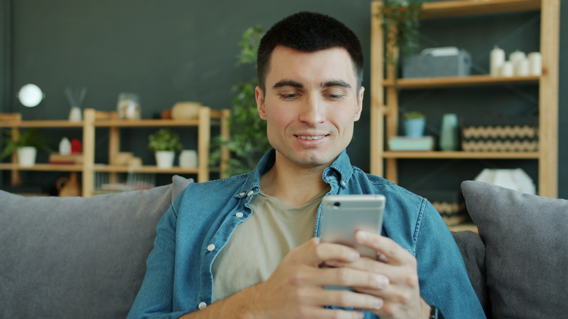 A man on his couch at home checking his banking app on his phone