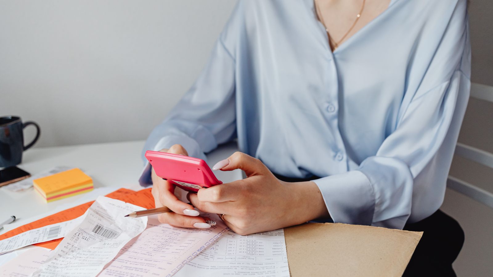 A woman working through her bills with a calculator at her desk