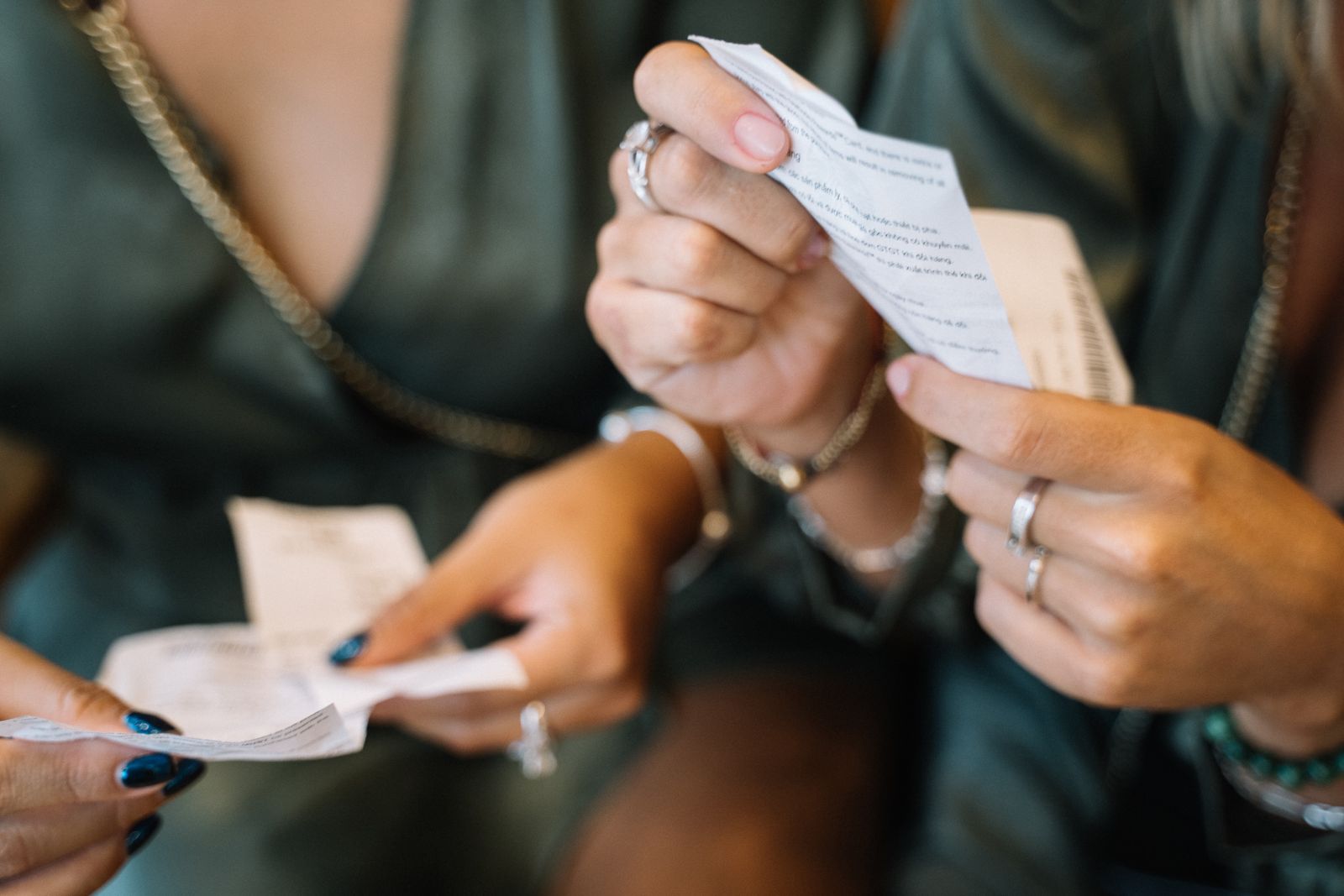 Close-up of two people holding and checking paper receipts.