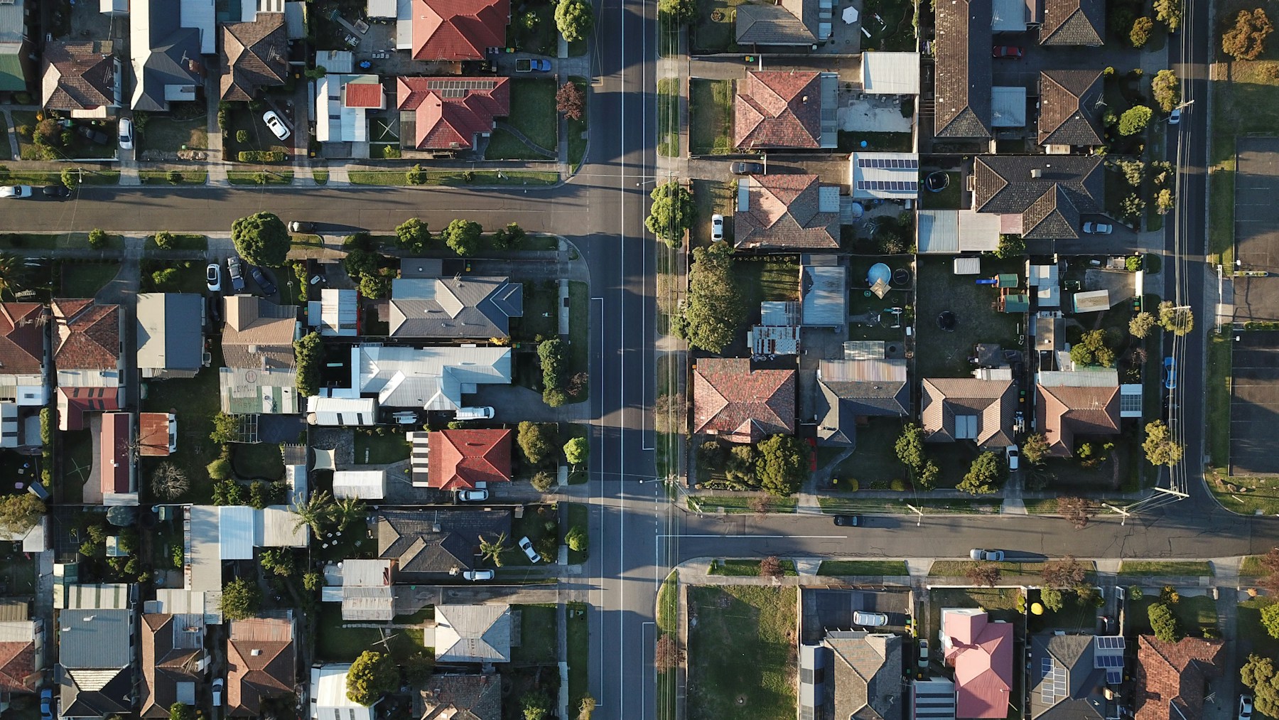Aerial view of Melbourne houses and intersecting streets in late afternoon light.