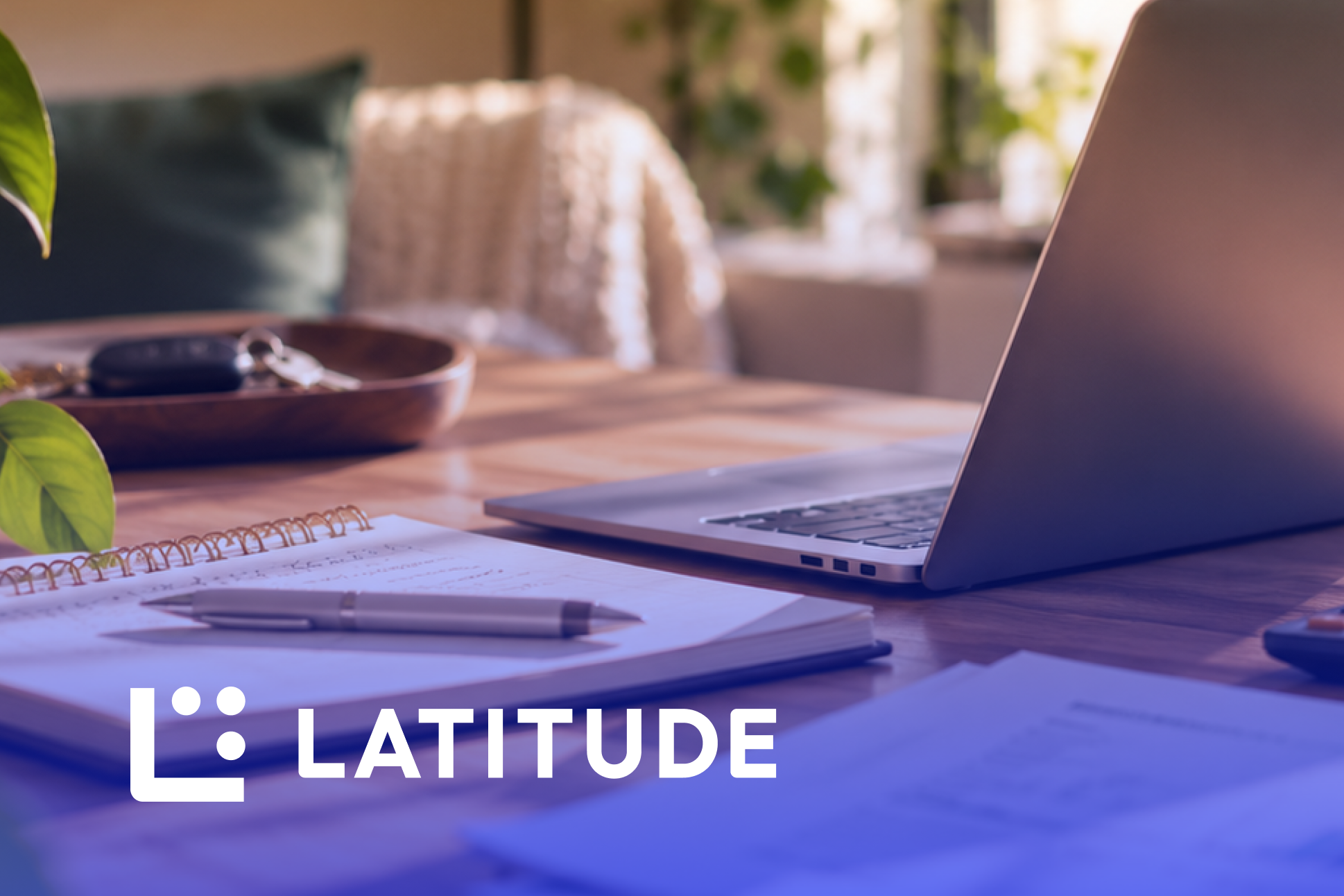 Latitude logo over a desk with a notebook, pen and laptop