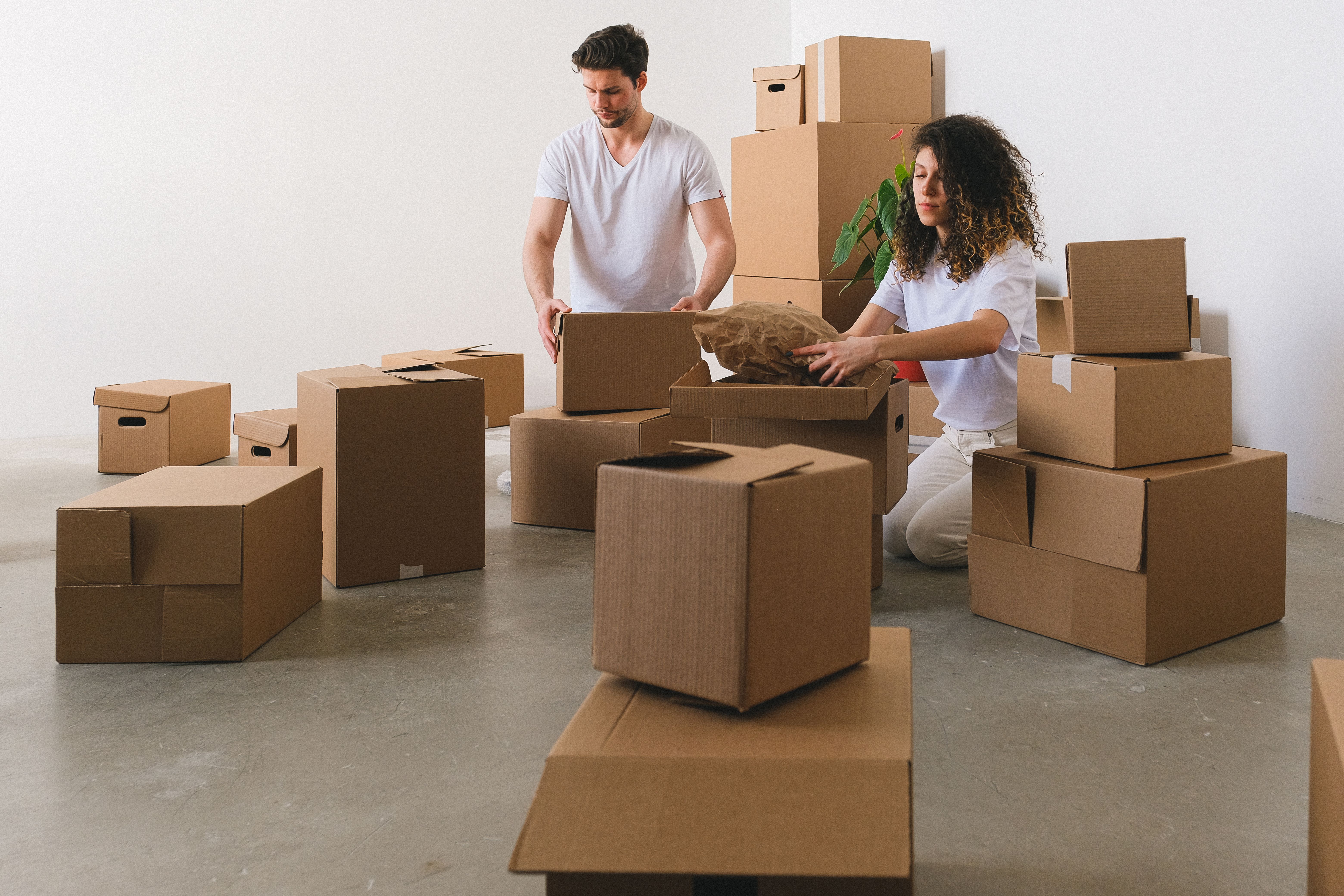 Two people packing household belongings into cardboard boxes