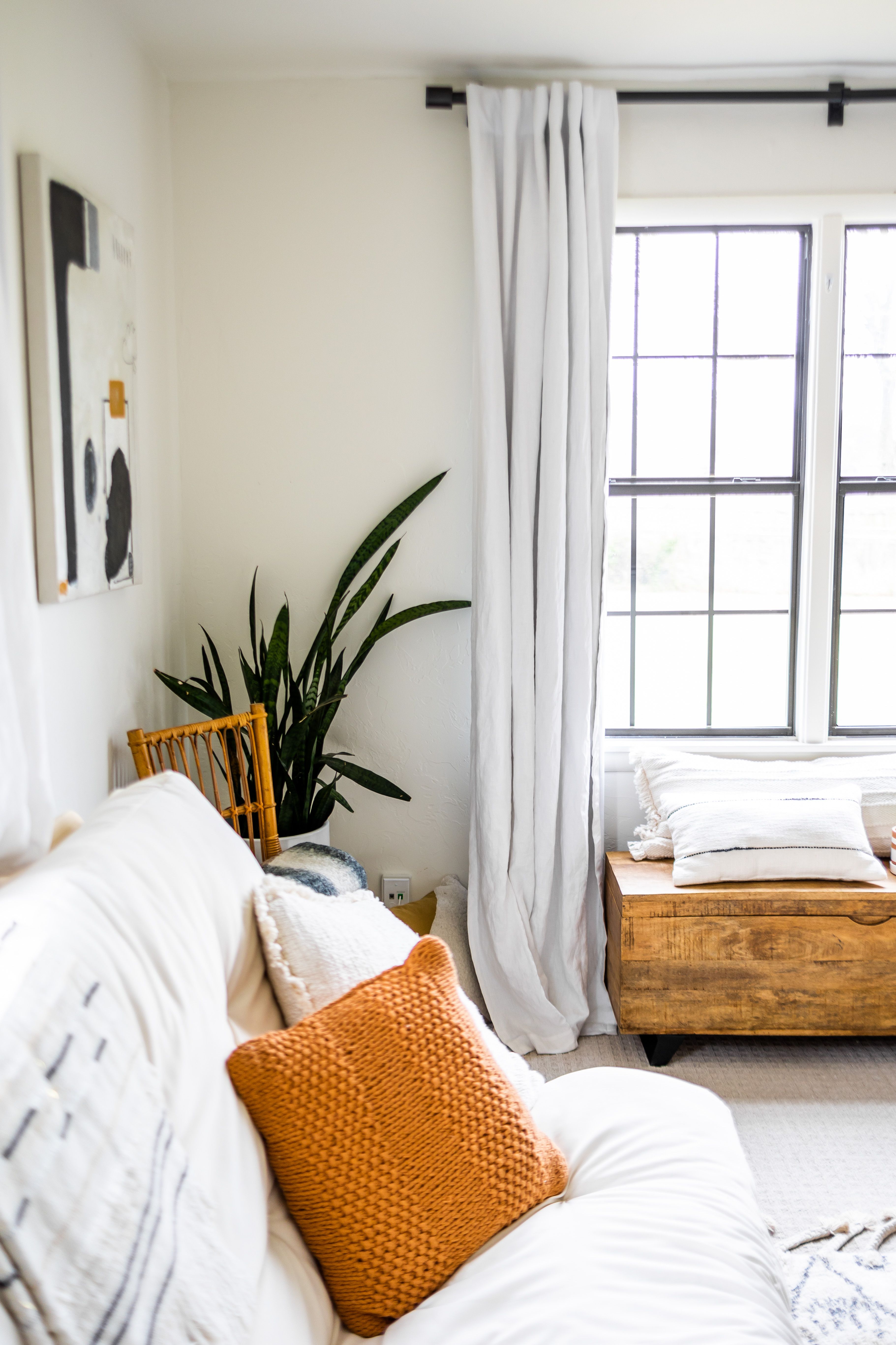 A sofa with cushions beside a bright living-room window