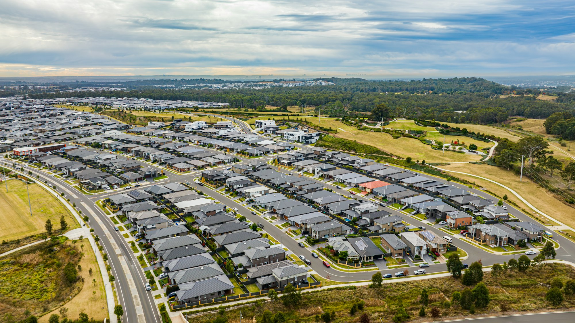 Aerial view of houses, streets and green parkland in a Sydney neighbourhood