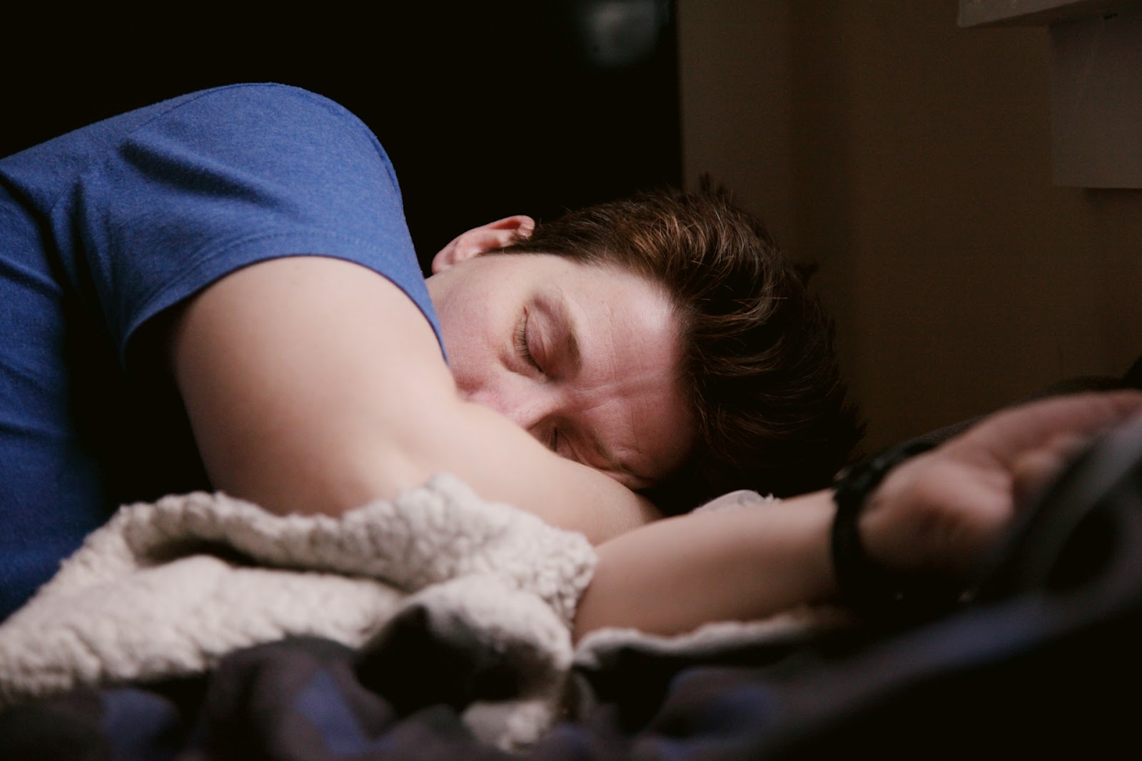 A man peacefully sleeping on a bed, surrounded by soft pillows and blankets.  