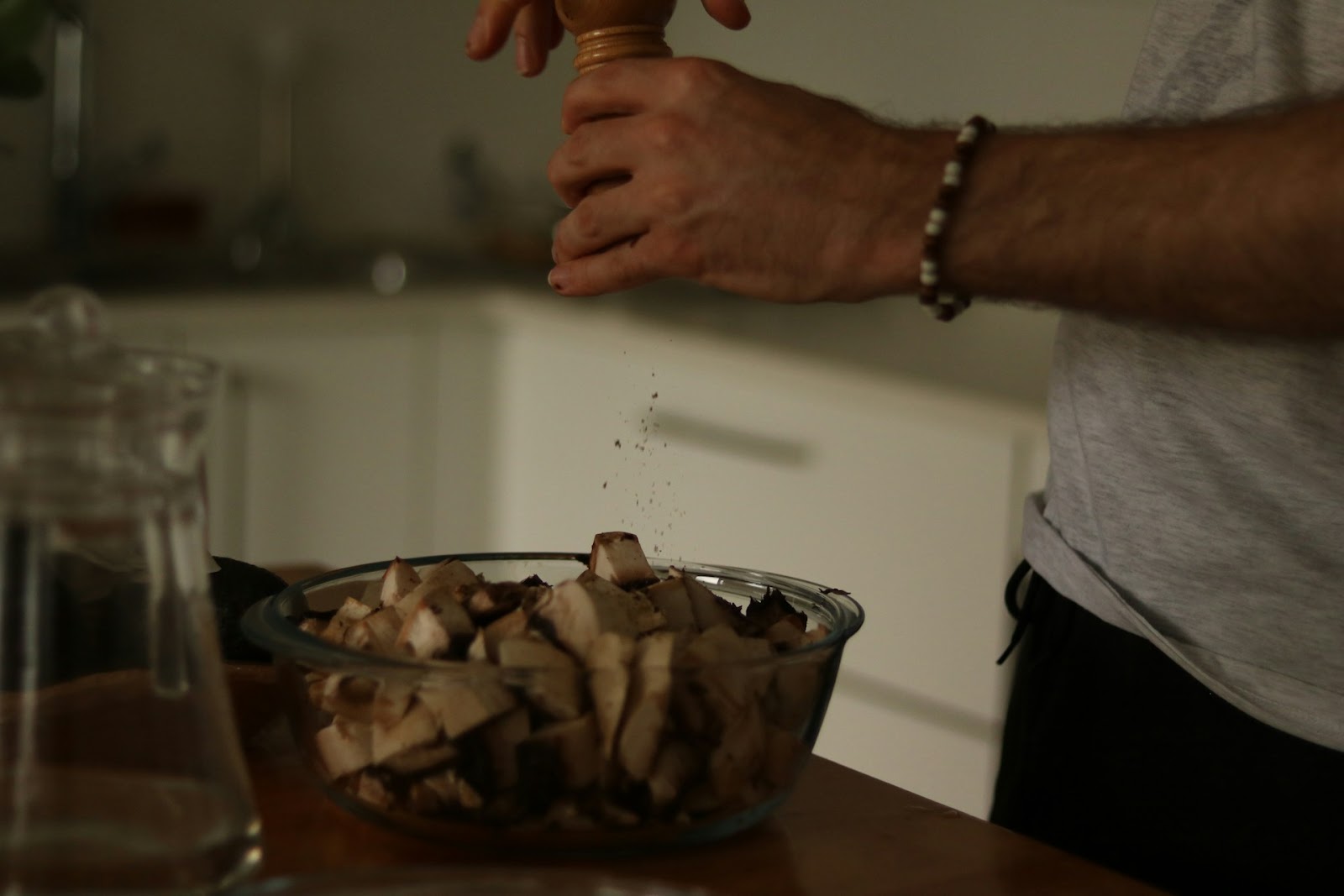 A man sprinkles mushrooms into a bowl, preparing ingredients for a dish.
