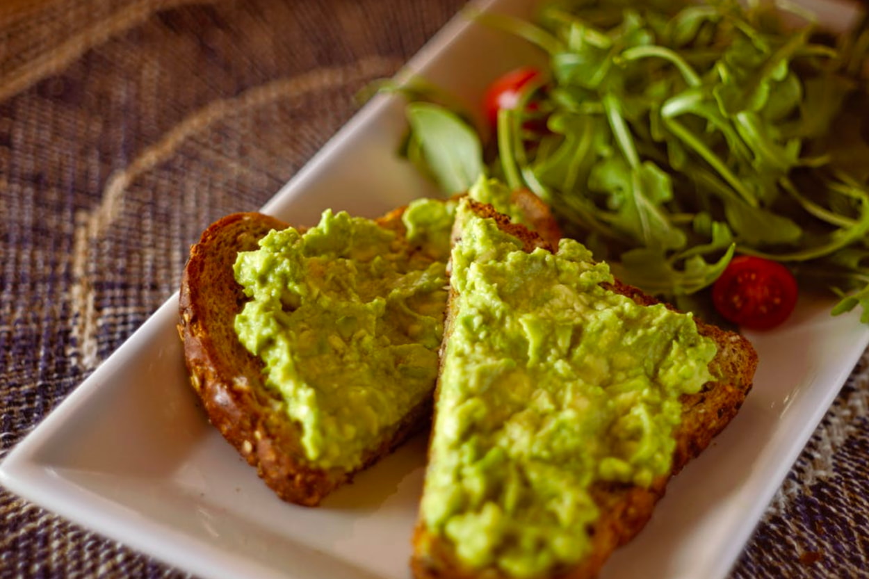 A white plate featuring a sandwich alongside a fresh salad.